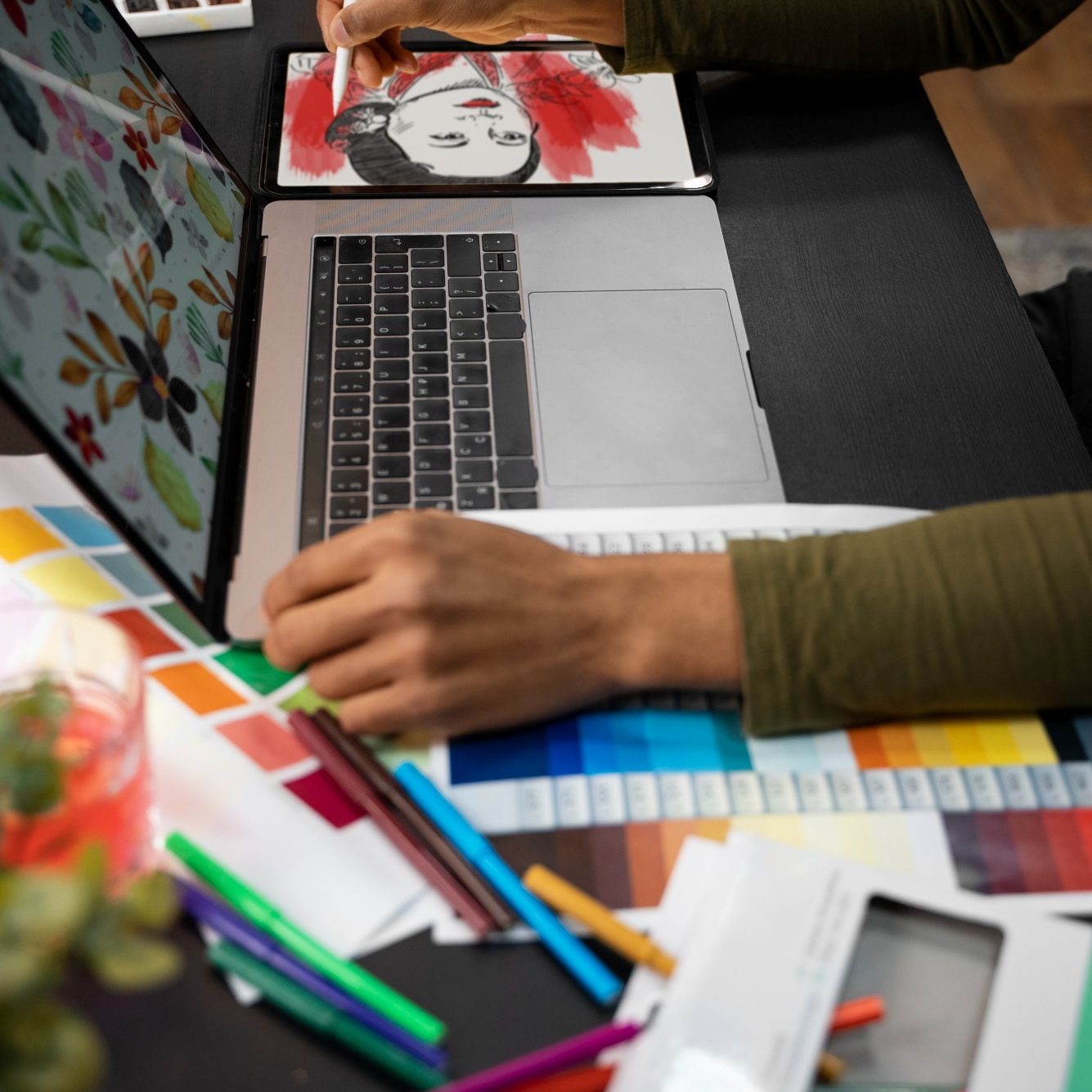 Mesa de trabajo con laptop, boceto artístico y materiales de color.